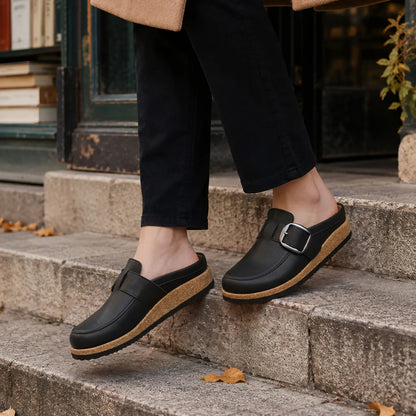 Black vegan leather clogs worn on stone steps