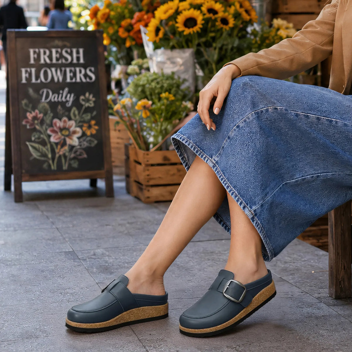 Navy vegan leather clogs worn with a denim skirt outdoors