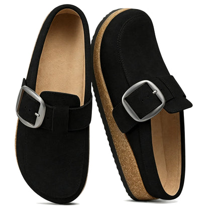 Black genuine suede mule clog worn while walking on a city street, side view
